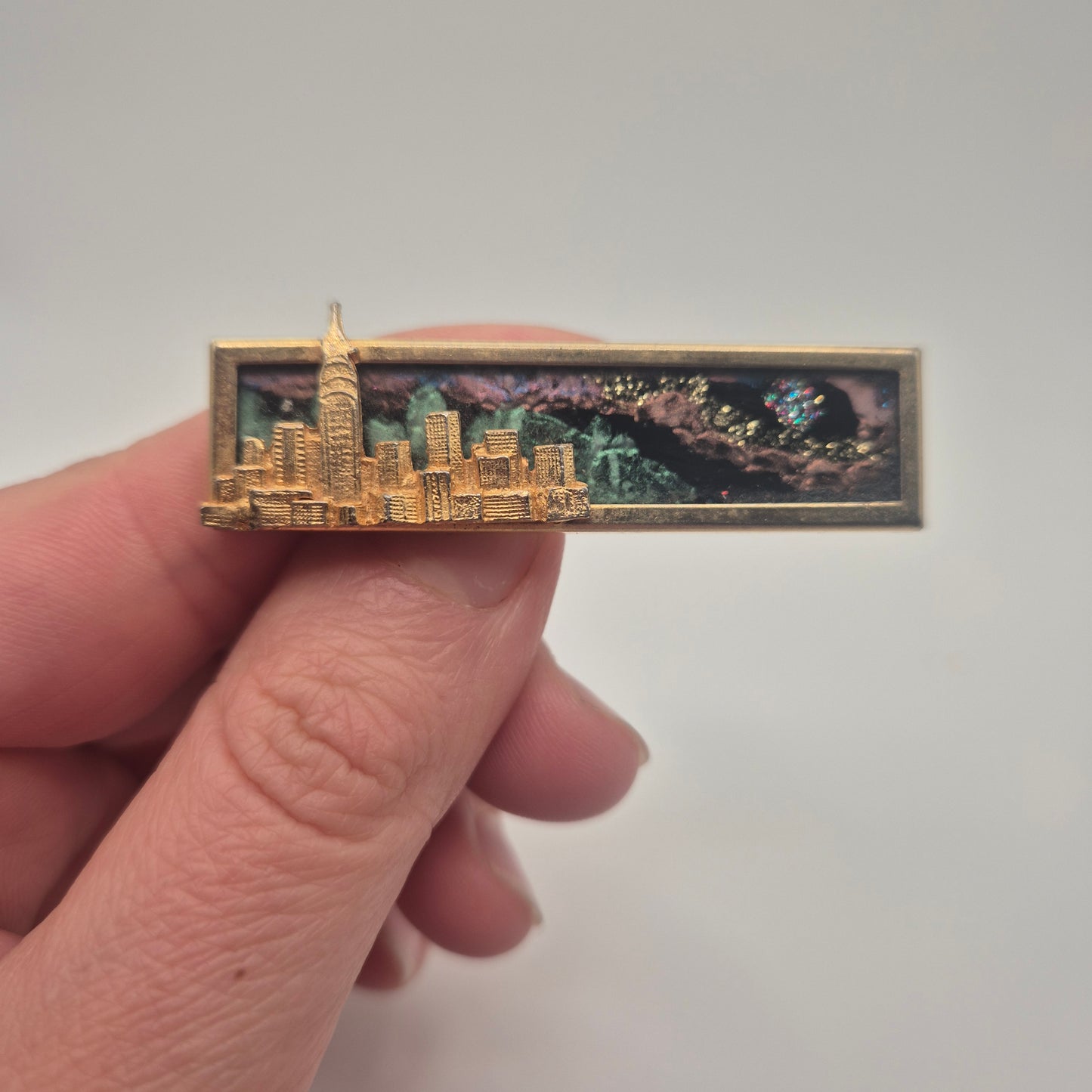 Vintage-Brosche – Goldene Skyline vor kosmischem Hintergrund New York