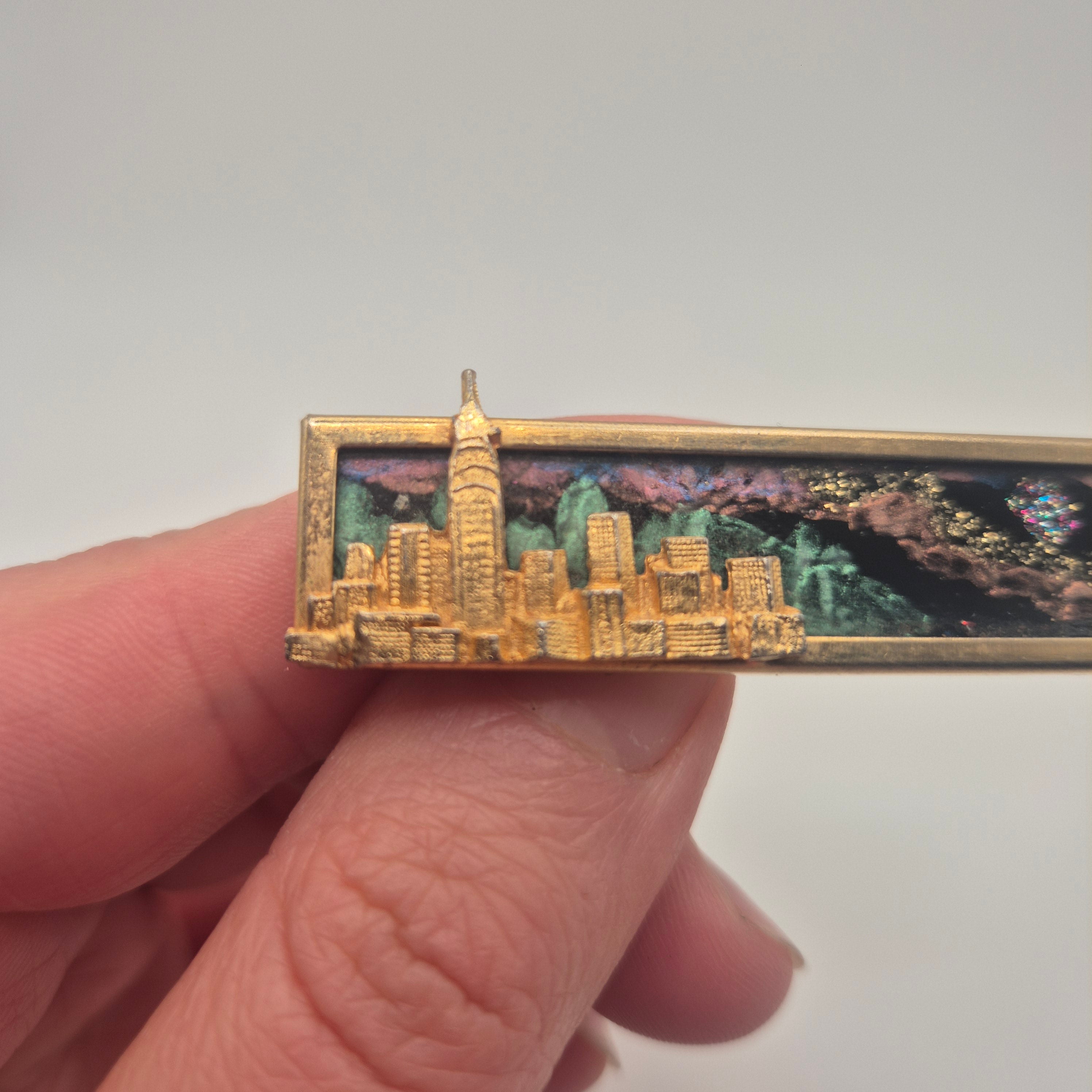 Vintage-Brosche – Goldene Skyline vor kosmischem Hintergrund New York