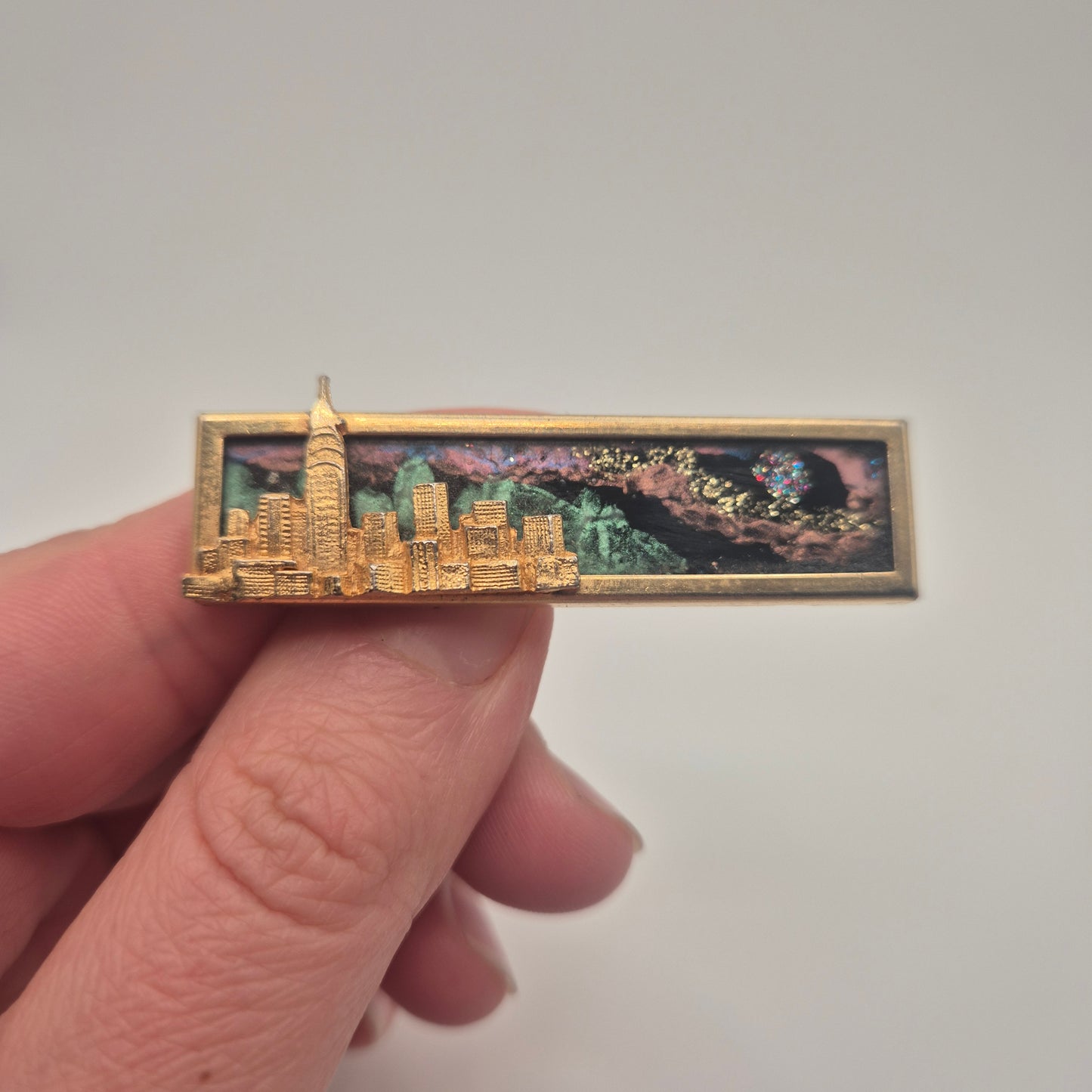 Vintage-Brosche – Goldene Skyline vor kosmischem Hintergrund New York